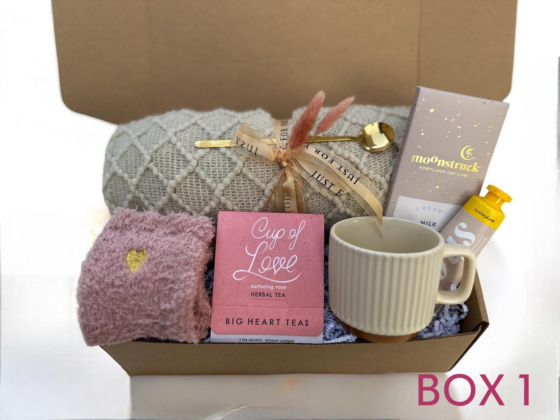 a box with a cup, a mug, a blanket, a tea bag,